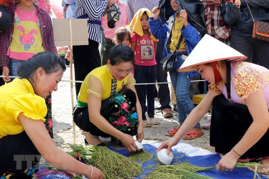 傣族同胞用小碗把谷粒刮落。越通社记者 越勇 摄
