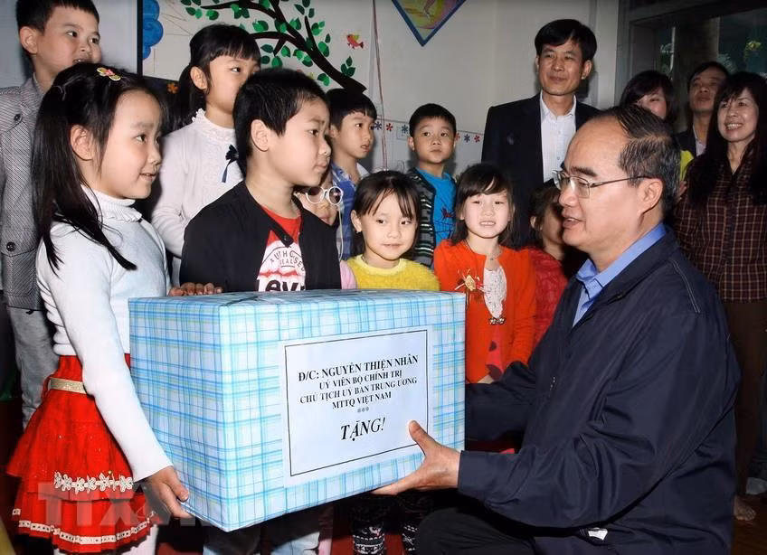 越南祖国阵线中央委员会主席阮善仁2015年3月27日向河内市丹凤县新会幼儿园的儿童们送上礼物。越通社发