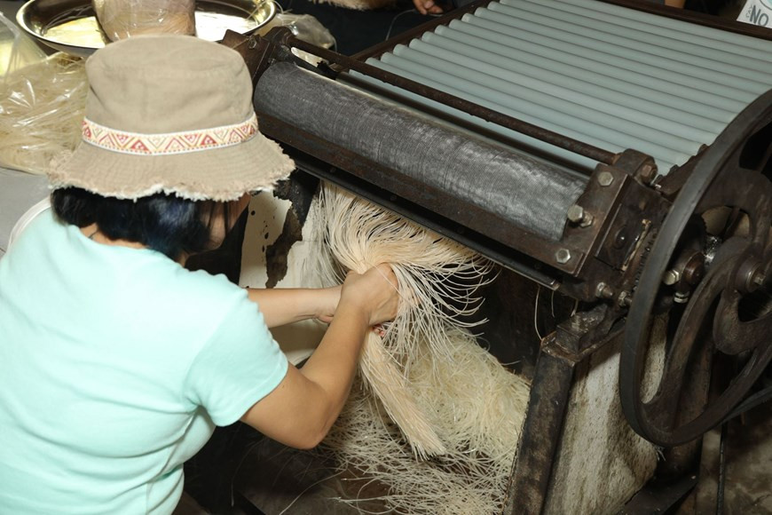 将晒好的薄饼放入专用工具切成细条。图自Vietnam+