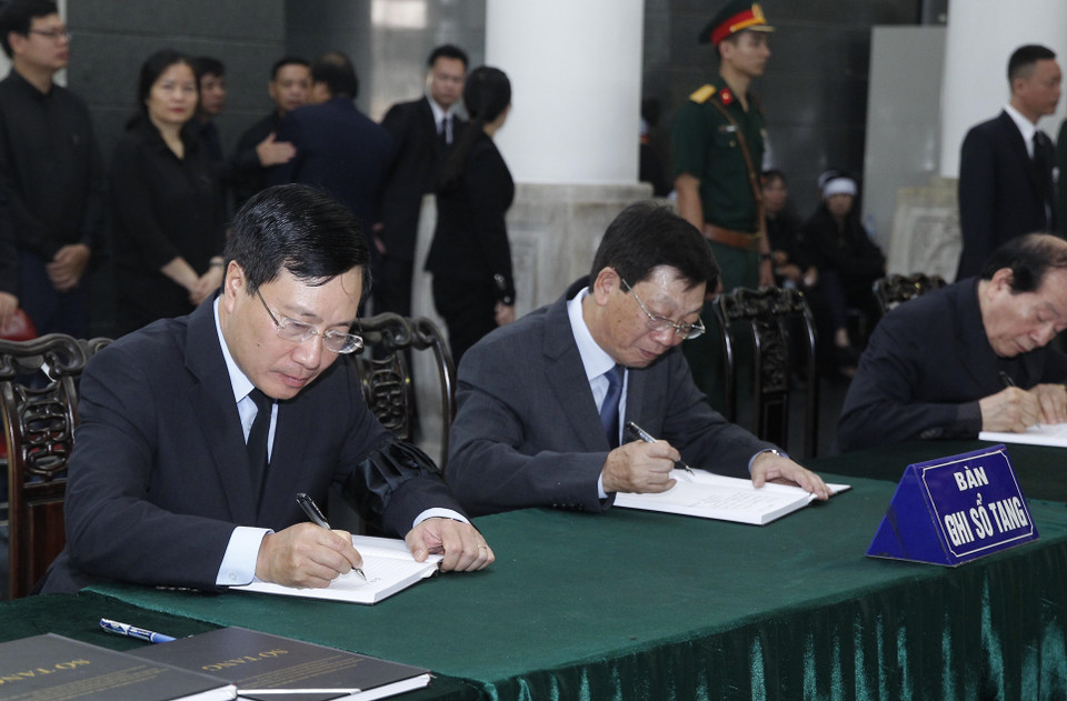 政府副总理兼外长范平明和原河内市人民委员会主席阮世草在留言簿上留言。（图片来源：越通社）