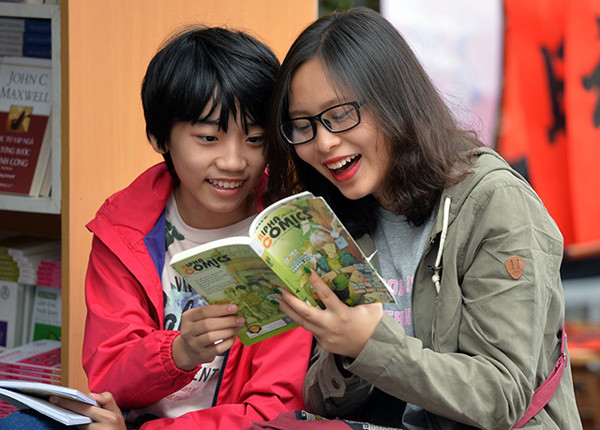 小朋友们聚精会神地看刚买到的书。(图片来源：越南《人民报》)