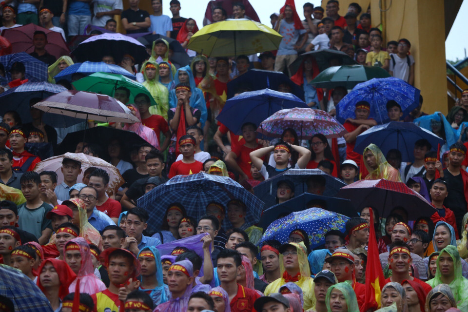 越南球迷一边淋雨一边为喜爱的球星呐喊助威。图自越通社