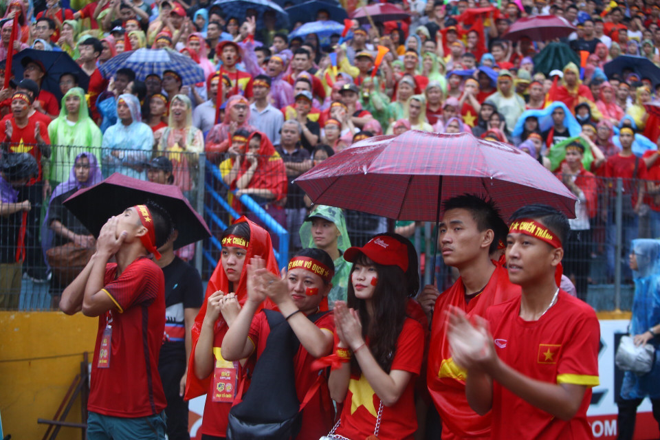 越南球迷一边淋雨一边为喜爱的球星呐喊助威。图自越通社