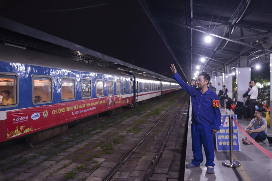 乘务员向乘坐爱心火车返乡的旅客挥手告别。