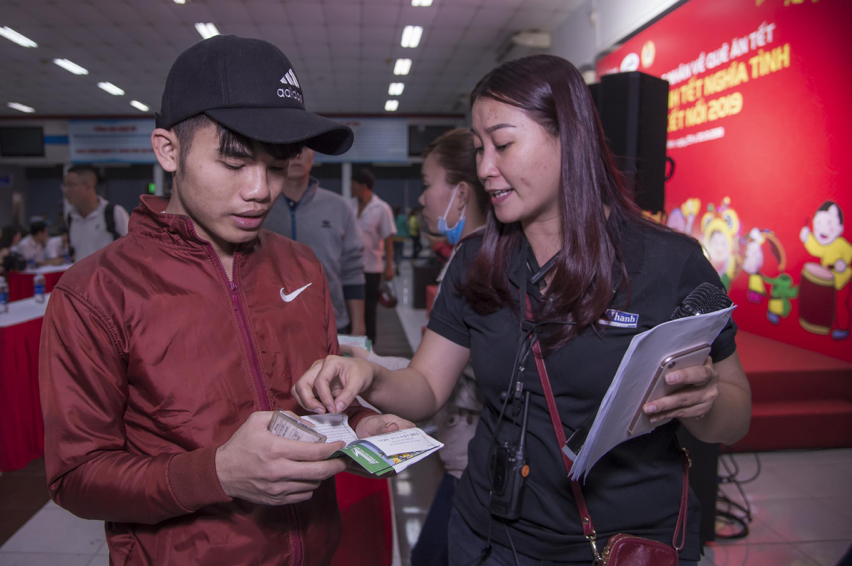 工作人员向工人介绍取票和乘坐火车的程序。
