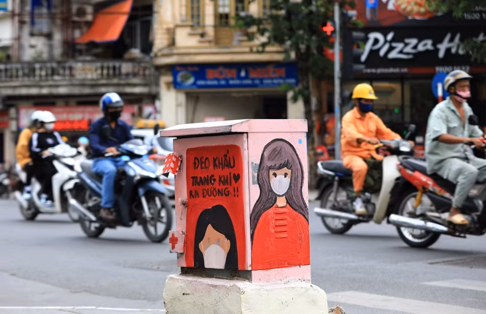 街头电箱上画满了五彩缤纷的防疫宣传画，吸引了路人的目光。图自越通社
