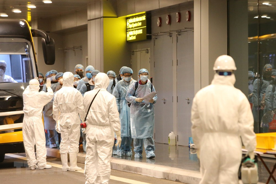 在医务人员的监控下，越南公民进行消毒和办理手续。越通社记者 杨江 摄