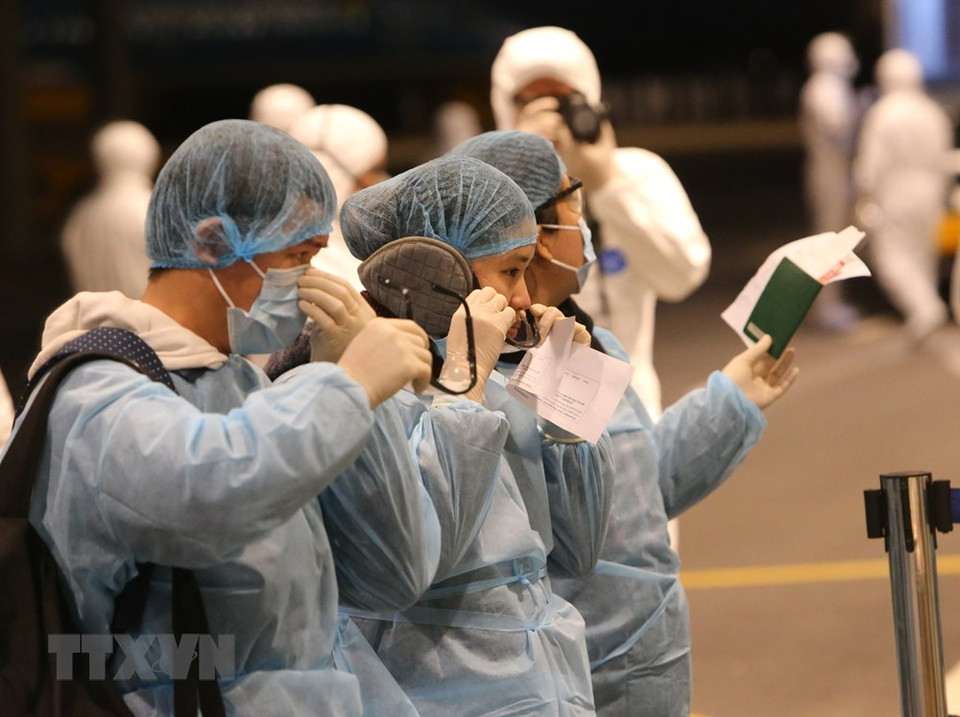 从中国武汉市归来的越南公民在云屯国际机场穿上消毒防护服并办理入境手续。越通社记者 杨江 摄