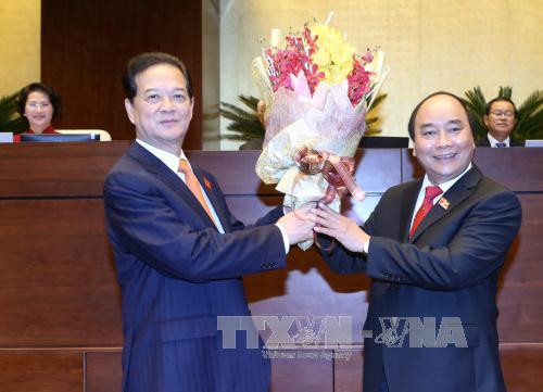 新任政府总理阮春福向原政府总理阮晋勇送花。（图片来源：越通社）