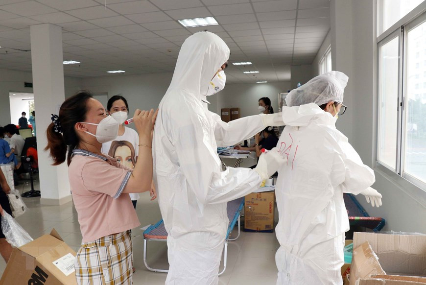 参与疫情防控的医护人员由于穿上防护服后看不清楚脸，便想出了在防护服后背写上各自名字的方法。图自越通社