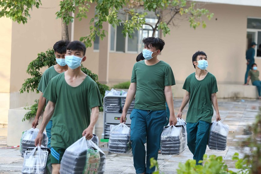 军队战士将饭盒送到新冠肺炎患者治疗区。图自越通社