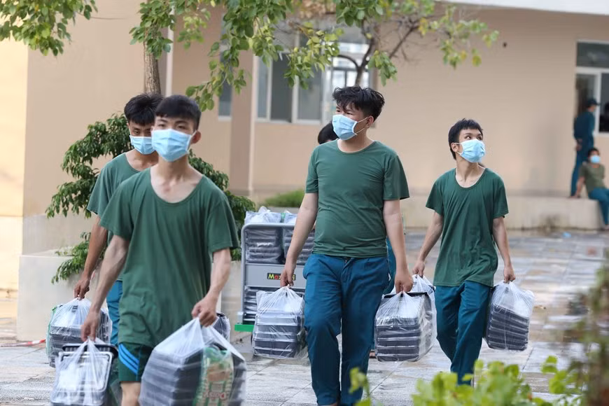军队战士将饭盒送到新冠肺炎患者治疗区。图自越通社