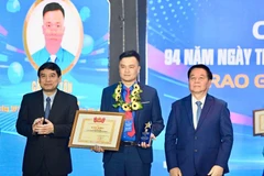 越共中央政治局委员、中央书记处书记、中央宣教与民运部部长阮仲义与越南国会文化教育委员会主任阮德荣为李自仲奖获奖者颁奖。胡志明共青团中央委员会供图