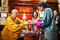 镇国寺住持释清雅和尚向越南国家主席梁强的夫人阮氏明月与不丹王后吉增·佩玛·旺楚克赠送菩提叶。图自越通社