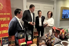 越南驻加拿大商务参赞陈秋琼向加拿大咖啡协会主席罗伯特·卡特介绍越南咖啡。图自越通社