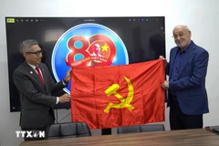 越南驻以色列大使李德忠向以色列共产党政治局委员、哈达什阵线主席伊萨姆·马库尔赠送党旗。图自越通社