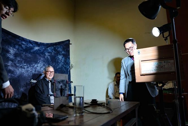 参观者体验旧时摄影方式拍照。图自越通社 vna-potal-khai-mac-photo-hanoi-25-biennale-nhiep-anh-quoc-te-8379813.jpg