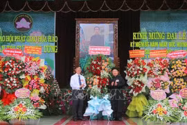 安江省越南祖国阵线委员会副主席裴文赠（左）送花祝贺和好佛教创立86周年。图自越通社