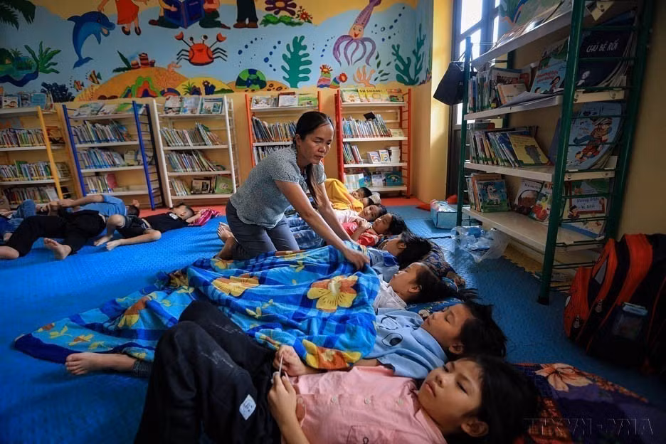 越南通过以人为本、具有人文关怀的政策措施，提高人口素质。图中：和平省山富学校的一名老师照顾让村的学生。图自越通社