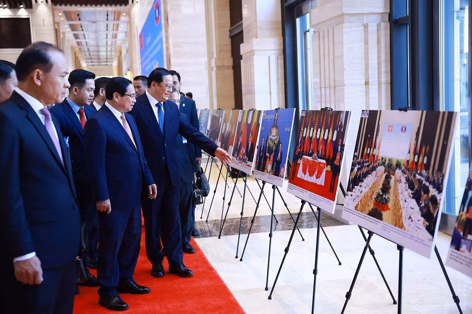 越南政府总理范明政与老挝政府总理宋赛·西潘敦共同参观两国合作图片展。图自越通社