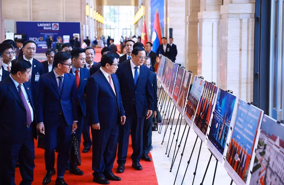 越南政府总理范明政与老挝政府总理宋赛·西潘敦共同参观两国合作图片展。图自越通社