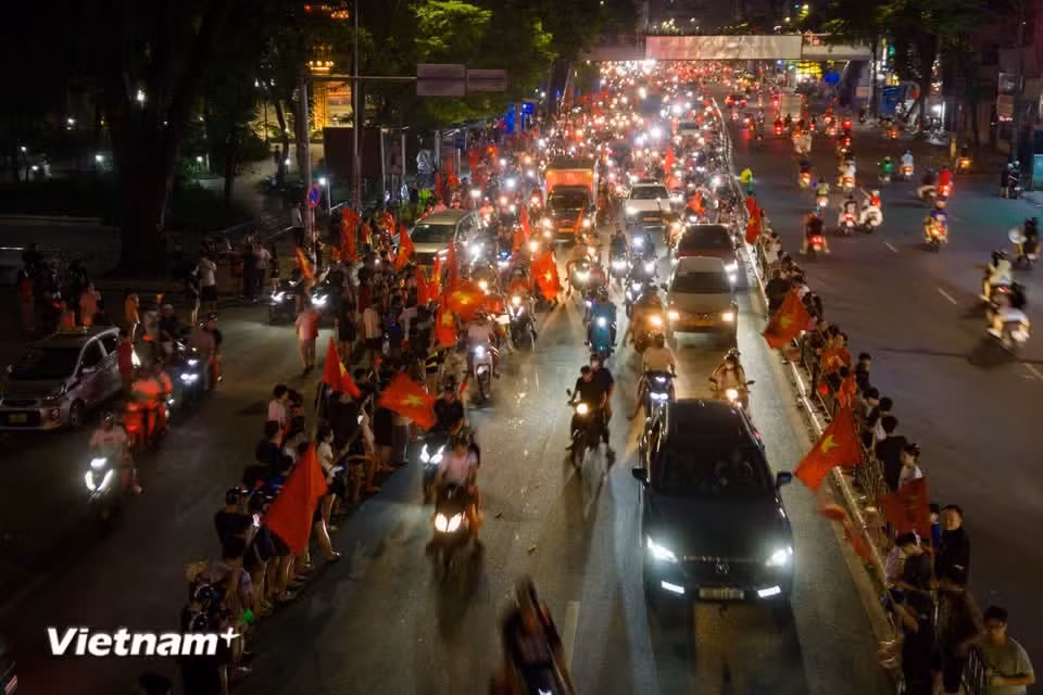 熙熙攘攘的人群和车辆穿梭其间。国旗的鲜艳红色、红色T恤和横幅映入眼帘，几乎覆盖了所有视线。图片来源：Vietnam+