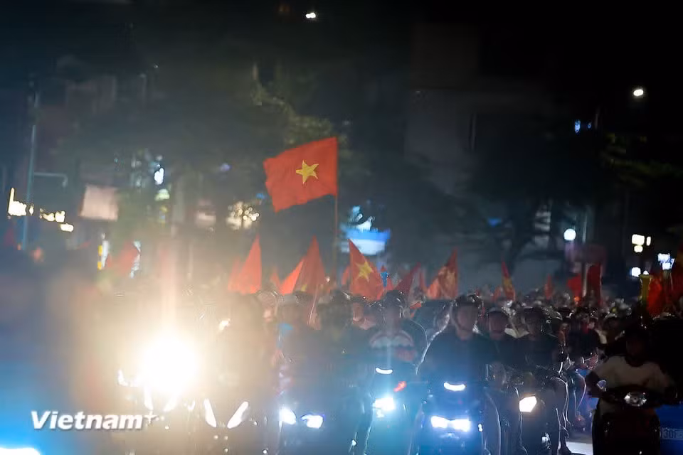 夜色渐深，庆祝气氛却愈发高涨，一面面巨幅国旗在璀璨灯光下迎风飘扬。图片来源：Vietnam+