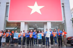 越南通讯社青年团在总部与大型国旗合影留念。图自 越通社