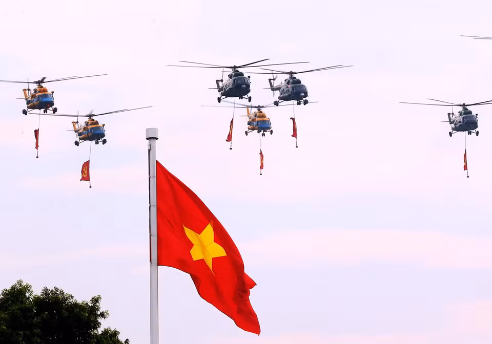 Mi-171、Mi-17、Mi-8直升机编队悬挂党旗与国旗飞越巴亭广场。图自越通社