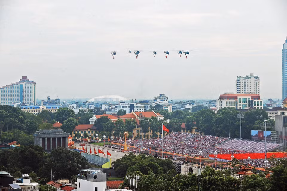 Mi-171、Mi-17、Mi-8直升机编队悬挂党旗与国旗飞越巴亭广场。图自越通社