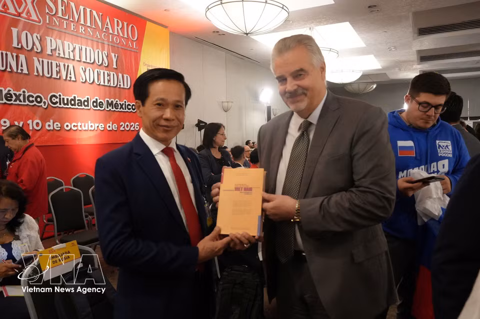 胡志明国家政治学院副院长黄福林向俄罗斯代表团团长赠送《新时代中实现越南强盛的渴望》一书。图自越通社