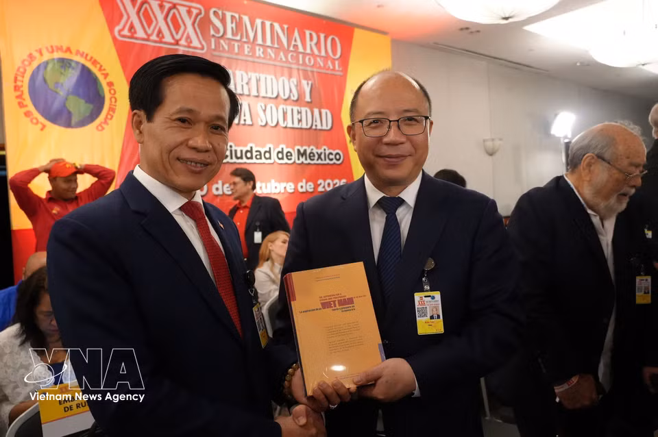 胡志明国家政治学院副院长黄福林向中国代表团团长赠送《新时代中实现越南强盛的渴望》一书。图自越通社