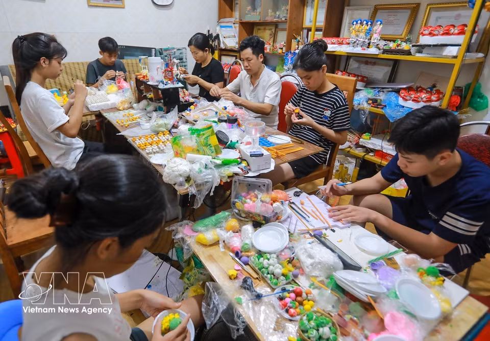 工匠邓文厚悉心指导年轻人制作面塑作品。图自越通社