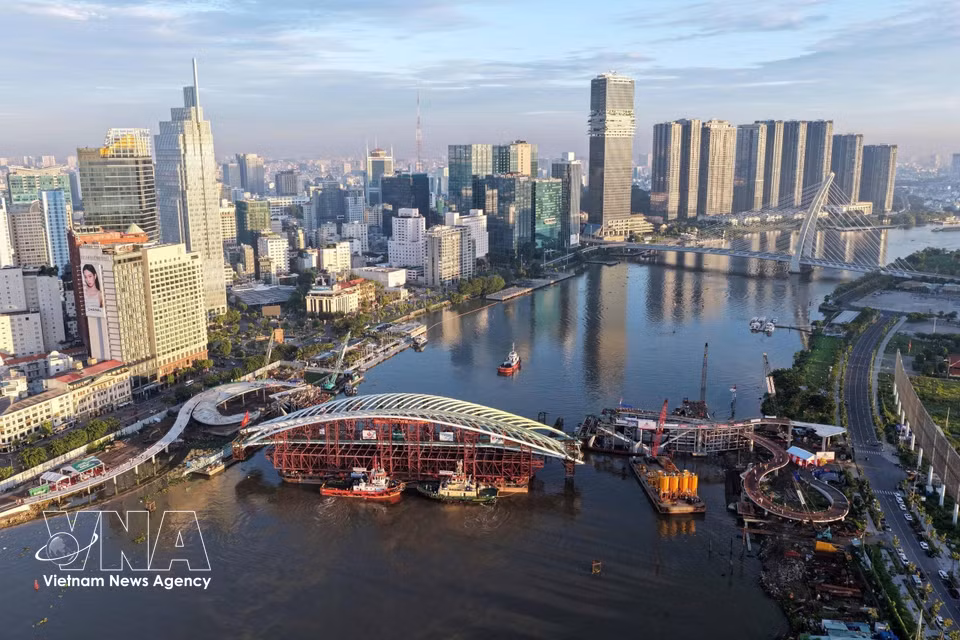 承载主跨的驳船被运至西贡河步行桥项目合龙位置的全景。图自越通社