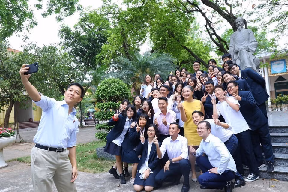 新加坡国会议长陈川仁在朱文安中学校园内朱文安雕像前与学生合影（河内，2022 年 5 月 19 日）。图自越通社