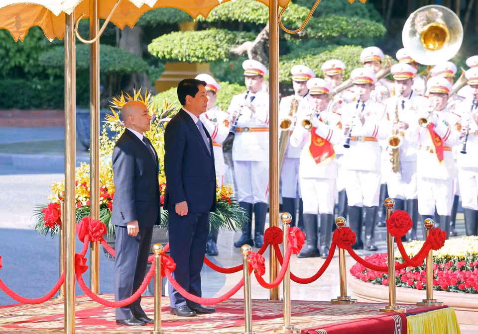 越南国家主席梁强和柬埔寨国王诺罗敦·西哈莫尼登上荣誉主席台，聆听军乐奏响两国国歌。图自越通社