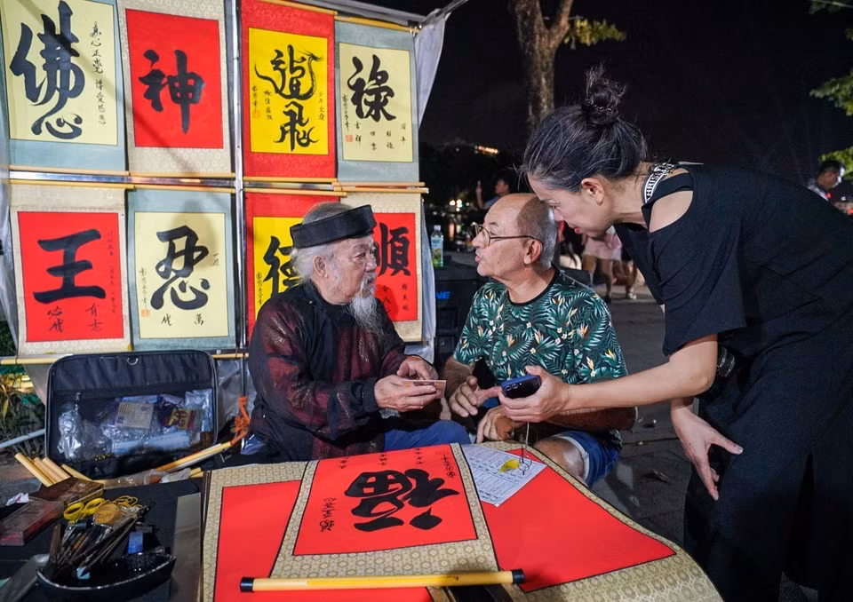 外国游客在还剑湖步行街求字。图自越通社