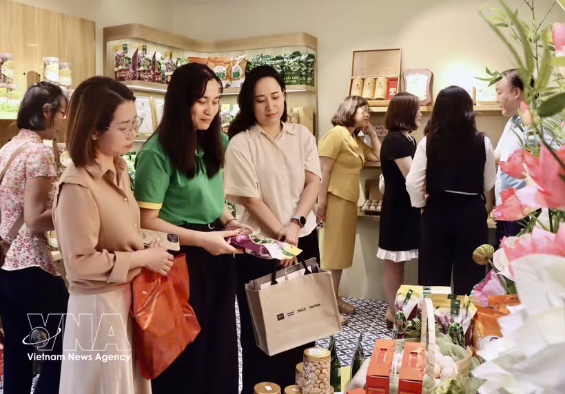 参观者在陈列展台前观看通过社交平台推广的商品。图自越通社