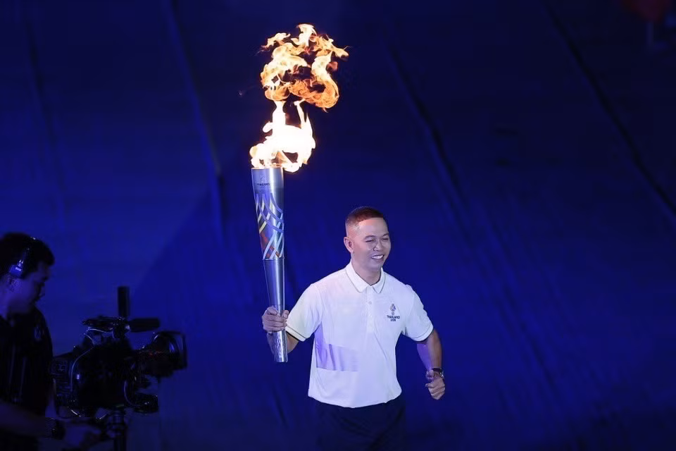 东道主的知名运动员们进行火炬传递仪式，点亮第33届东南亚运动会主火炬台。图自越通社