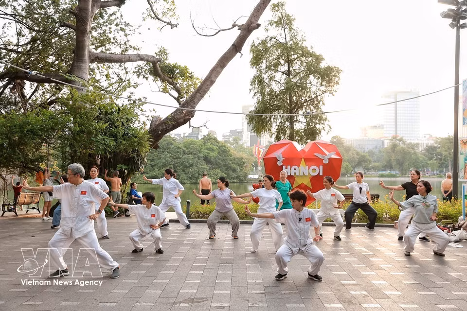 一群老年人在还剑湖畔练习太极拳。图自越通社