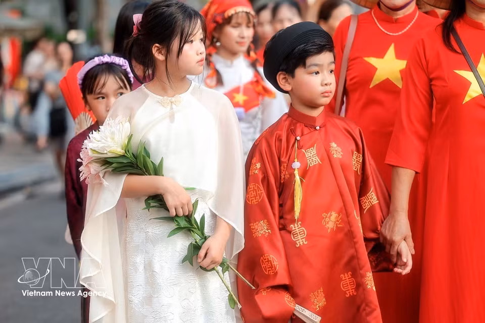 身着越南传统服饰的小朋友参加“异彩五洲”街头艺术节。图自越通社