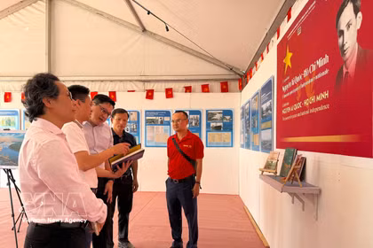 《人民报》代表向越南驻法国大使Kalamoungkhoune Souphanouvong（中）介绍有关胡志明主席和越南争取民族独立历程的展览内容。图自越通社